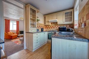 a kitchen with wooden cabinets and a counter top at CAPRI 13 SA - Cosy 2 bed house, Close to M1 & Loughborough University, Free WIFI, Free PARKING, - Ask for contractor rates! in Loughborough