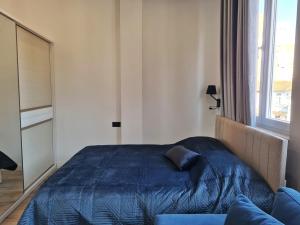 - une chambre avec un lit bleu et une fenêtre dans l'établissement Cane Apartments, à Tirana