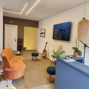 a living room with a tv and a couch and a chair at Casa Arrô - Pousada Boutique in Itajaí