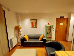 a living room with a black couch and yellow pillows at Lotila Flats Cabañaquinta in Aller