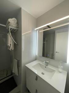 een witte badkamer met een wastafel en een spiegel bij alcossebrerelax in Alcossebre
