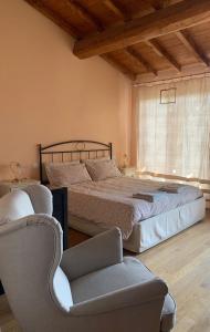 a bedroom with a bed and a chair and a window at Agriturismo Il Filare in Neviano degli Arduini