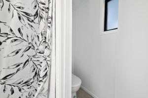 une salle de bain avec toilettes et rideau de douche dans l'établissement Pihanga Cottage - Kuratau Bach, à Kuratau 16 autres photos
