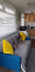 a blue couch with yellow pillows in a living room at Once Upon a Tide - Bridlington Chalet in Bessingby