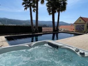 un jacuzzi con palmeras en el patio trasero en Maison chaleureuse avec piscine et spa, en Vale de Cambra