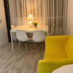 stół jadalny z 2 krzesłami i żółtą kanapą w obiekcie Mieszkanie 2 pok 2 min do morza w mieście Sopot
