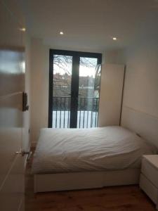 um quarto com uma cama branca e uma janela em Luxury Penthouse Apartment ( Private Gated) em Londres