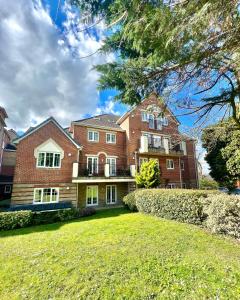 a large brick house with a lawn in front of it at 2 Bed Serviced Apartment with Balcony, Free Parking, Wifi & Netflix in Basingstoke in Basingstoke
