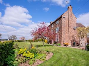 an old brick building with a garden in front of it at Rimmers Farmhouse in Wichenford