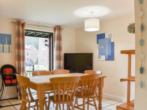 ein Esszimmer mit einem Tisch, Stühlen und einem TV in der Unterkunft Riverside Cottage in Whitby