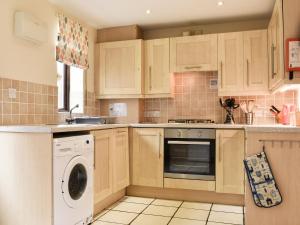 a kitchen with wooden cabinets and a washer and dryer at Riverside Cottage in Whitby