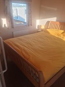 a large bed in a bedroom with a window at The Pearl - Deluxe Access Caravan in Skegness