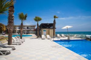 un complejo con piscina, sillas y el océano en Panamericana Hotel Arica, en Arica