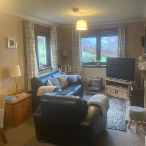 a living room with a couch and a flat screen tv at Craigavon Cottage in Ballachulish