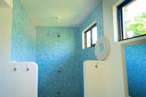 W łazience z prysznicem znajdują się niebieskie ściany wyłożone kafelkami. w obiekcie Hostel Esperanza w mieście Pavones