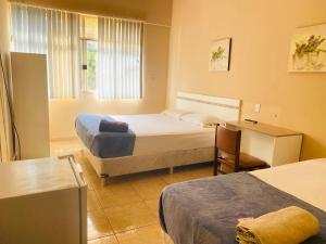 1 dormitorio con 2 camas, escritorio y ventana en Turis Hotel, en Ciudad del Este