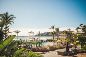 ośrodek z basenem i plażą z palmami w obiekcie Avila Lighthouse Suites w mieście Avila Beach