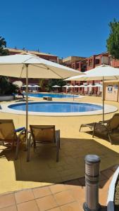 basen z 2 parasolami i 2 krzesłami w obiekcie Apartment Punta Umbría Luxury w mieście Punta Umbría
