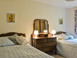 a bedroom with two beds and a dresser with a mirror at Crubisdale in Blairmore