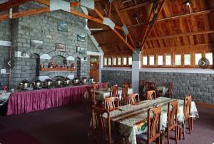 a dining room with tables and chairs and a stone wall at Arcadian 3Skies Gupis in Gupis