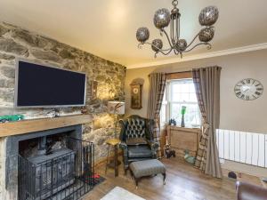 a living room with a fireplace and a tv on a stone wall at Fern Cottage in Ardentinny