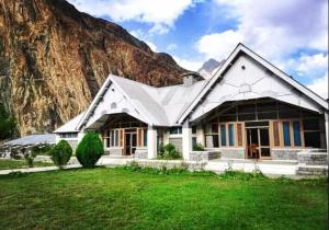a white house with a mountain in the background at Arcadian 3Skies Gupis in Gupis