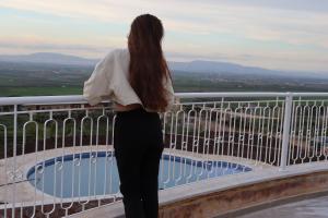 une femme debout sur un balcon donnant sur une piscine dans l'établissement Bhalil Farm House, à Séfrou