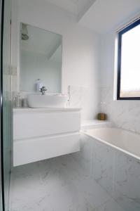 biała łazienka z umywalką i wanną w obiekcie BLK Stays Guest House Deluxe Units Caboolture South w mieście Caboolture