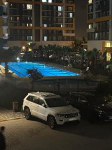 a white car parked next to a swimming pool at night at Fascinating 1 bedroom with pool view balcony in Antalya