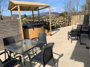 a patio with a table and chairs and a grill at Moneydarragh Cottage with uninterrupted mountain and sea views- Hot tub available for hire in Annalong
