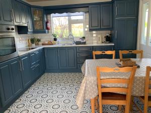 a kitchen with blue cabinets and a table with chairs at Moneydarragh Cottage with uninterrupted mountain and sea views- Hot tub available for hire at extra cost in Annalong