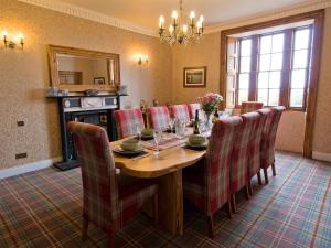a dining room with a wooden table and chairs at Drummuie House in Golspie