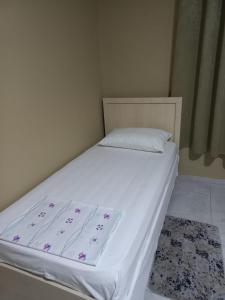 uma cama com lençóis brancos e flores roxas em Klev's apartments em Shkodër