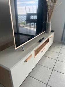 a tv on a white cabinet with a television on it at Beach studio in Punaauia