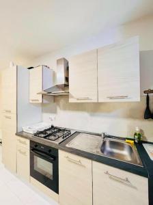 cocina con armarios blancos, fregadero y fogones en Sliema Apartment in balluta bay, en Sliema