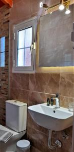 un bagno con lavandino, water e finestra di Stefanosplace ApartHotel Sea View a Barbati