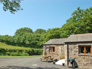 een stenen hut met een picknicktafel en een bank bij The Stables in Bodmin