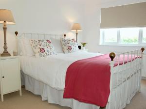 a bedroom with a white bed with a red blanket at The Lookout in Port Isaac