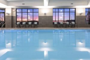 a swimming pool with tables and chairs in a building at Residence Inn Minneapolis Maple Grove/Arbor Lakes in Maple Grove