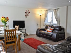 The Lodge - 29794 في Swimbridge: غرفة معيشة مع أريكة جلدية وطاولة
