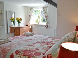 a bedroom with a bed with a floral bedspread at The Lodge - 29794 in Swimbridge