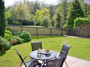 a table and chairs in a yard with a fence at The Lodge - 29794 in Swimbridge