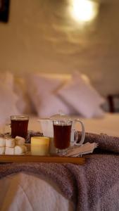 a tray with two cups of tea and butter on a bed at Tuki Llajta - Pueblo bonito Lodge in Huancayo