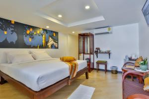 a bedroom with a white bed with a painting on the wall at Chedi Home -SHA Extra Plus in Chiang Mai