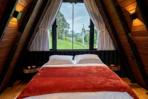 a bed in a room with a large window at Altitude 1140 Urubici - Chalés in Urubici