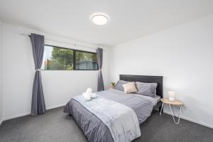 a white bedroom with a bed and a window at Newly Built Two Bedroom with Double Garage in Wigram