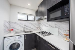 a kitchen with a washing machine and a microwave at Newly Built Two Bedroom with Double Garage in Wigram