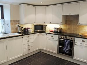 a kitchen with white cabinets and a microwave at Prideaux Cottage in Luxulyan