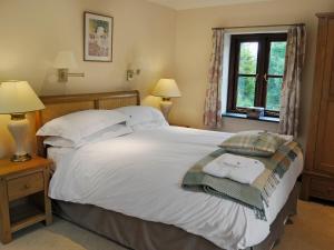 a bedroom with a large white bed and a window at Prideaux Cottage in Luxulyan