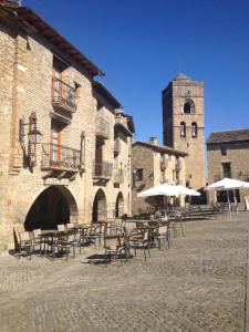 un patio con mesas y sillas y una torre de reloj en Los Siete Reyes, en Aínsa